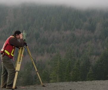 a man in a red vest and a yellow vest is holding a tripod