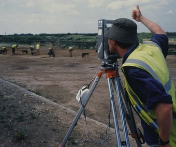 a man in a yellow vest and a camera on a tripod