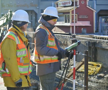 two men in safety vests standing in front of a building