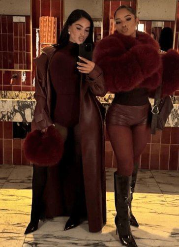 two women in leather jackets and boots standing in front of a mirror