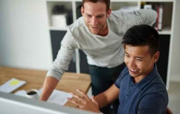 2 man are looking at a computer screen