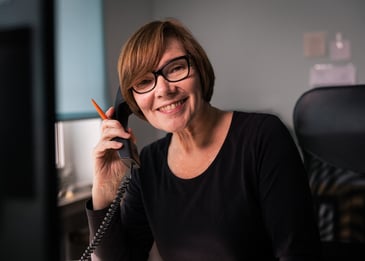 eine Frau in schwarzem Shirt ist in an einem Telefon im Büro