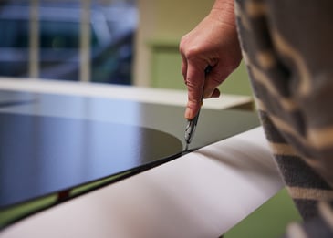 Professioneller Druck auf Alu dibond wird mit einem cutter Messer beschnitten, Hand Hält Werkzeug