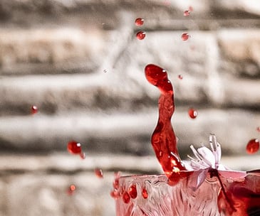 Schizzo rosso da un cocktail in cristallo con fiore di ciliegio – fotografia emozionale e dinamica a