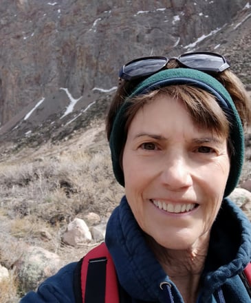 Susan Rensberger in the rugged Andes mountains wearing a headband and sunglasses on her head