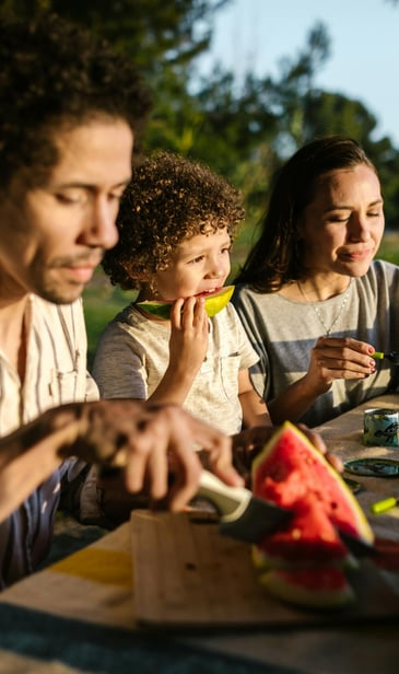 a family sitting at a table with a child eating nutritious foods