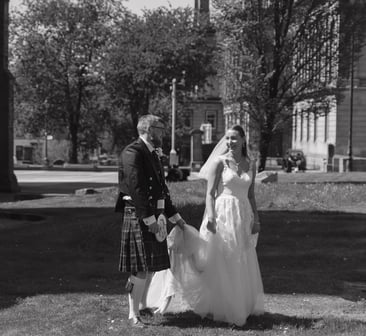a bride and groom in a field with a scottish flag
