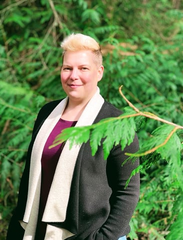 Therapist in a black cardigan standing in front of trees