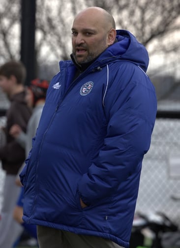 a man in a blue jacket coaching rugby