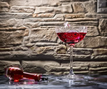 Cocktail rosso in coppa di cristallo con fiore di ciliegio su fondo in pietra – fotografia emozional