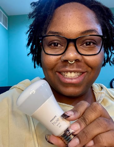 Ashley smiling and holding a philips hue lightbulb