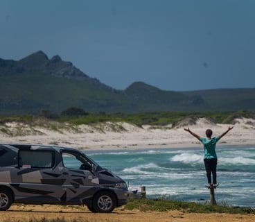 Man standing on short pole near car on beach