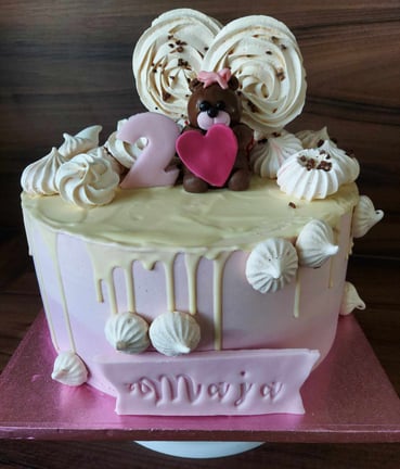 a cake with a teddy bear on top of a pink cake