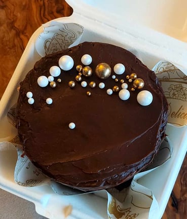 a cake in a styrofoam container with chocolate frosting