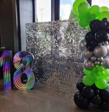 Silver shimmer wall with marquee number and balloons for an 18th birthday at Beenleigh Distillery.