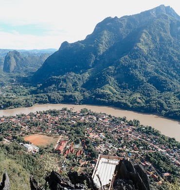 a mountain view of a town with a river and mountains in the background