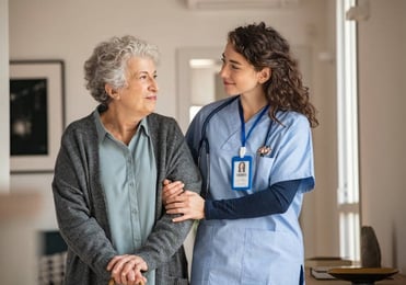 A nurse converses with an elderly woman in a hospital hallway, providing care and support.