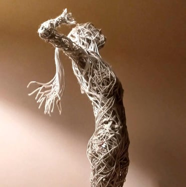 A cotton-covered wire sculpture of a standing female figure stretching with arms raised