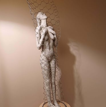 Clay sculpture of a female figure with hands gently placed on chest, surrounded by wire netting.