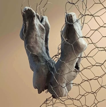 A sculpture of two female torsos, back to back, surrounded by wire netting, painted blue-greys