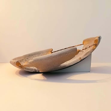Side view of a bowl-like sculpture with embossed horse figures and symbols in rust/brown hues