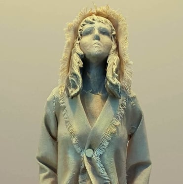 Clay and canvas sculpture of a female figure gazing upwards, wearing windswept, ragged clothes.