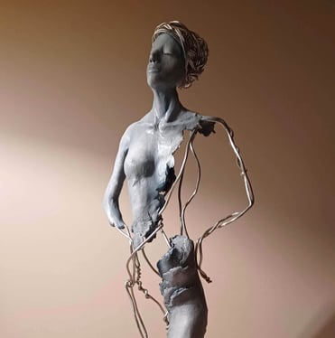 A complete sculpture of a standing female figure, part clay, part wire, hands on hips