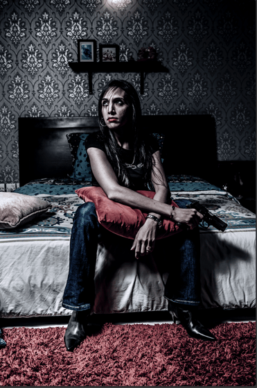 Cinematic portrait of woman with a gun, dramatic lighting, moody bedroom, fine art conceptual photo