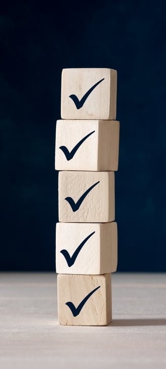 A stack of wooden blocks with tick check marks on them