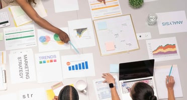 A group of people discussing marketing strategies with various documents and charts spread out on a table