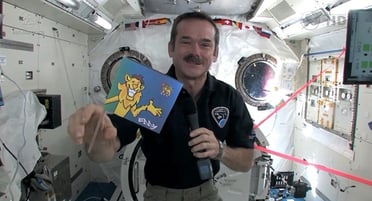 un astronaute tenant un drapeau dans la Station spatiale internationale