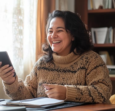 Mujer emprendedora sonriente revisa su celular, representa conexión, motivación, y trabajo independiente en casa.