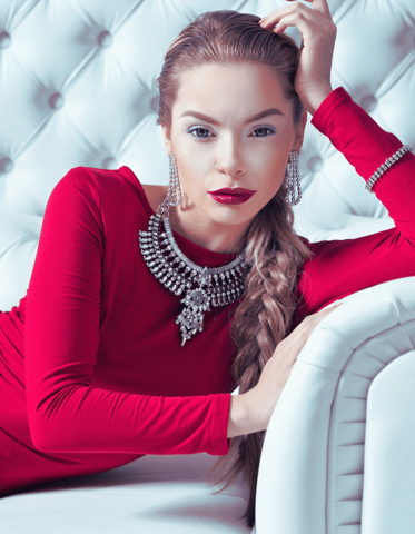 Elegant empowered woman in red dress on a white couch, symbolizing the CEO Metal Archetype in Phoenix Ignited Brand