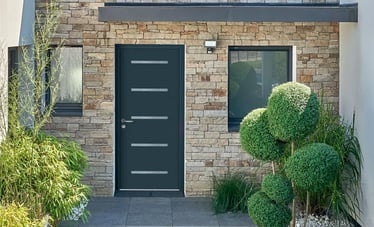Porte d'entrée en aluminium noir sur une maison à façade en pierre