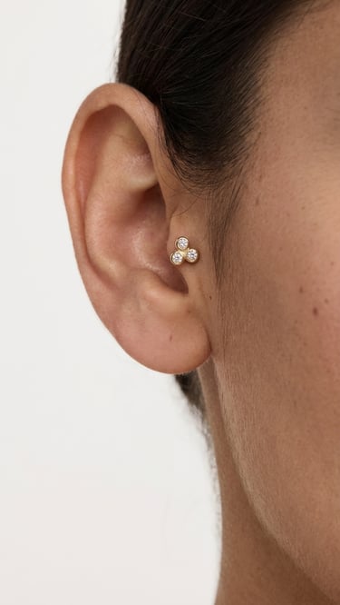 פירסינג טראגוס מזהב עם שלושה יהלומים נוצצים בעיצוב תלתן באוזן