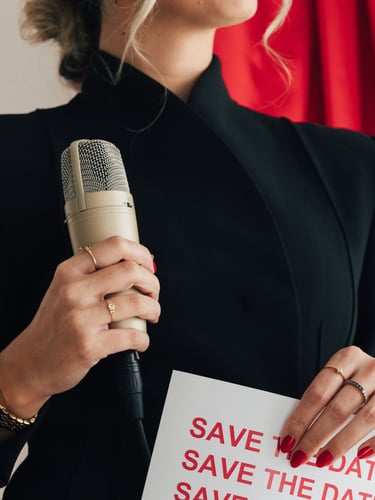 Primer plano de la presentadora de podcast sosteniendo un micrófono de estudio mientras sostiene un