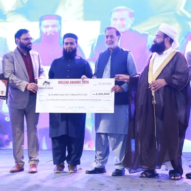 Meezab Awards 2024 ceremony featuring men presenting a large ceremonial check on stage for Hajj and Umrah services.