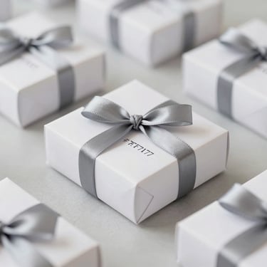 A set of personalized wedding gifts on a minimalist table, featuring clean lines and #7F7176 ribbon details, professional product photography.