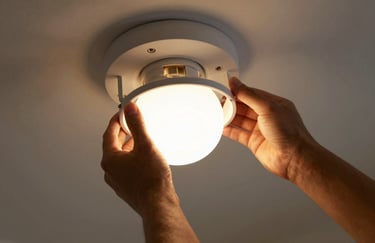 A close-up of a technician's hands carefully installing a modern light fixture in a North American / US home, focused warm lighting.