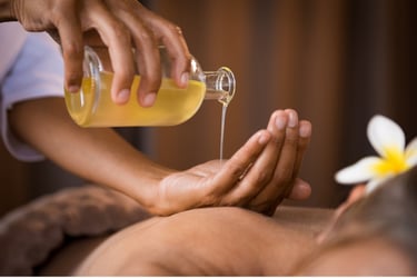 A massage therapist pouring essential aromatherapy oil into their hand for a relaxing spa treatment.