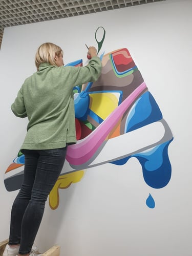 Artist realizând pictură perete sneaker.