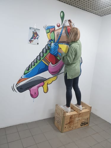 Artist realizând pictură perete sneaker.