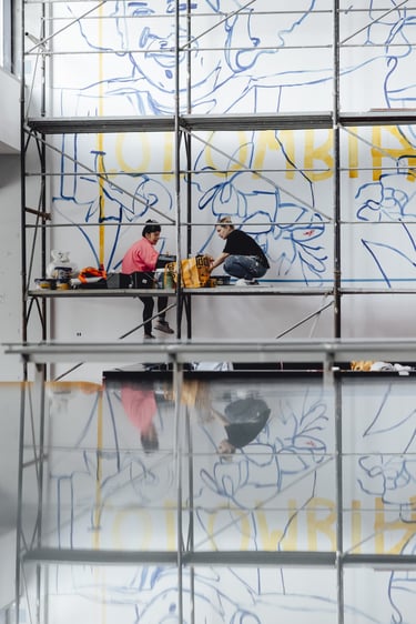 Artiști pe schelă trasând contururi pictură murală.