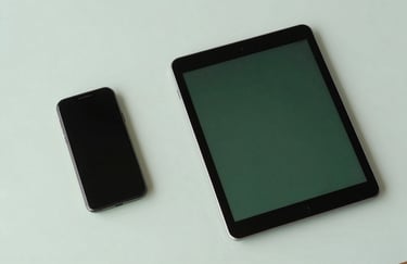 A top-down view of a clean desk with a smartphone and a tablet in a modern North American / US office, clean lines, professional lighting, featuring muted sage and dark forest green.