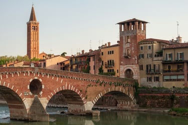 The historic brick arches of Ponte Pietra bridge crossing the Adige River in Verona, Italy.