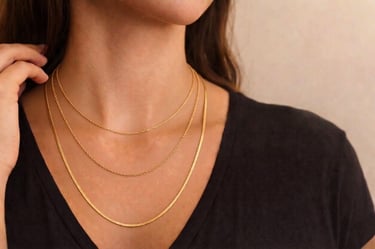 Woman wearing layered gold necklaces featuring a dainty rope chain and a flat herringbone snake chain.
