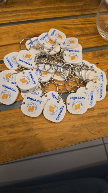 Custom white square Serenika keychains with blue text and yellow logos marketing 3d.