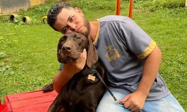 Homem sentado abraçando o seu cão. Conheça as raças de cães que não latem em apartamento. 