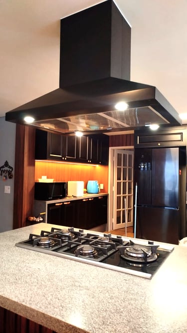 Coifa em aço inox com iluminação LED sobre cooktop, valorizando a ventilação e o design moderno