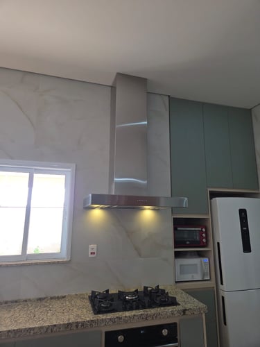 Cozinha moderna com coifa de aço inoxidável, bancadas de granito e eletrodomésticos embutidos.
